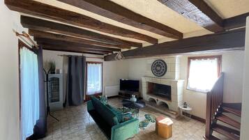 Una sala de estar con chimenea, un sofá, un televisor y una escalera.