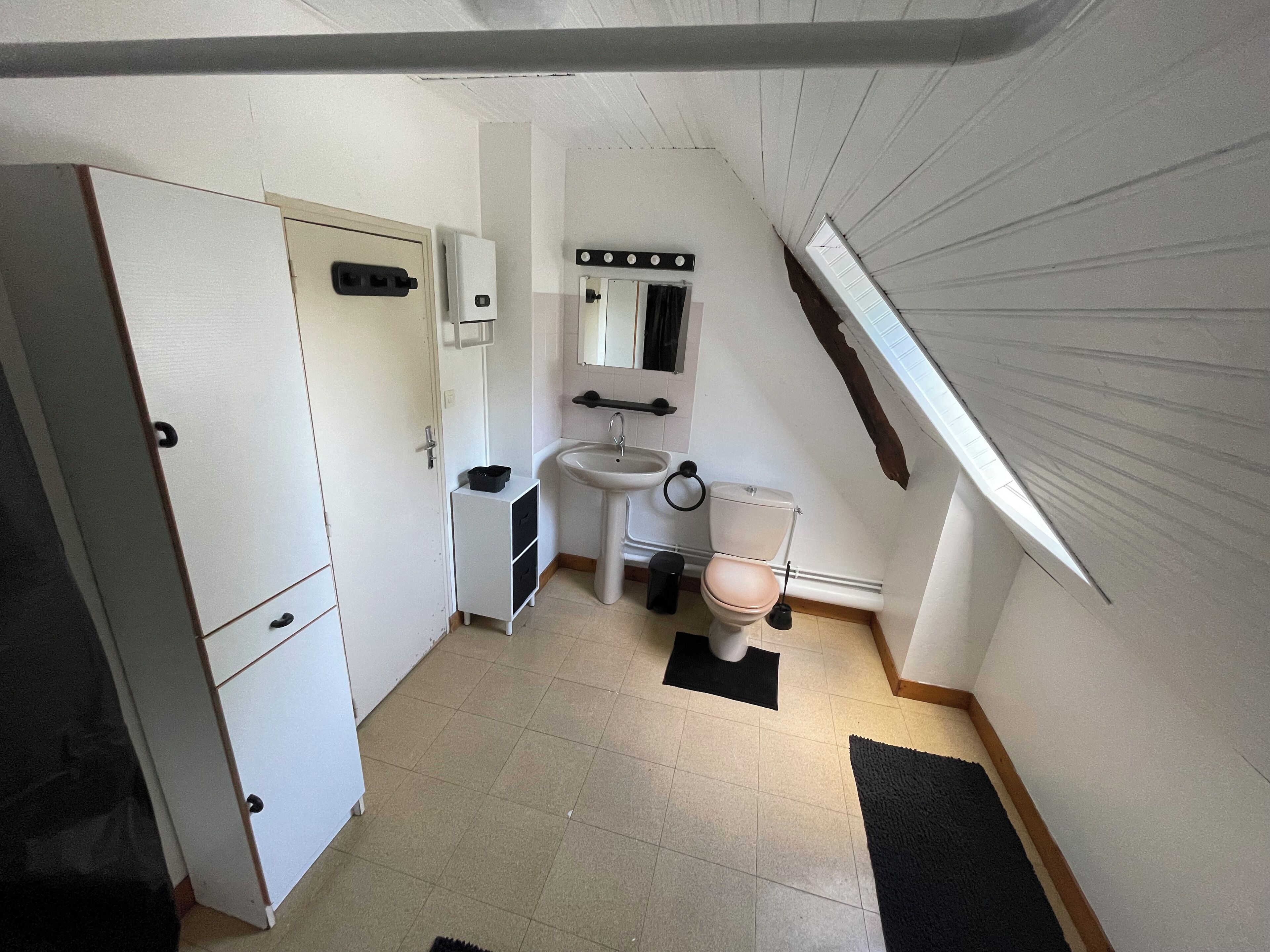 A compact, well-lit bathroom with a toilet, sink, and cabinet.