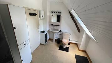 A compact, well-lit bathroom with a toilet, sink, and cabinet.