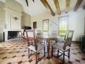 Cozy dining area with a round table and six chairs, fireplace, and TV.