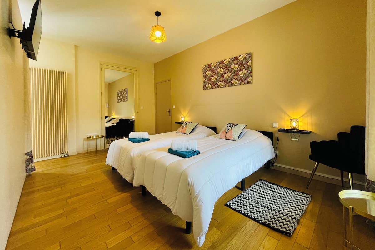 Quarto de hotel com duas camas, piso de madeira, televisão de tela plana na parede e luminária no teto.