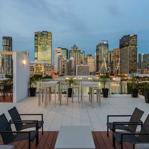 A rooftop terrace with outdoor seating, a city skyline view, and modern buildings. - 2BR with Parking | Walk to QPAC & South Bank (South Brisbane)
