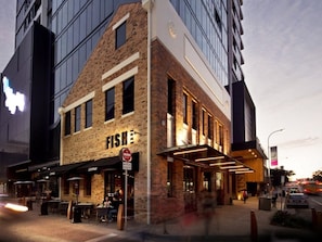 A building with a brick facade, a sign reading 'FISH LANE,' and a restaurant named 'CANON' with outdoor seating. - 2BR with Parking | Walk to QPAC & South Bank (South Brisbane)