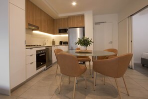 Una cocina moderna con comedor, que incluye una mesa redonda y cuatro sillas, un horno empotrado, microondas y un refrigerador.