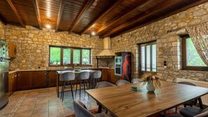 Una cucina rustica con pareti in pietra, travi in legno al soffitto e un'area pranzo con tavolo e sedie.