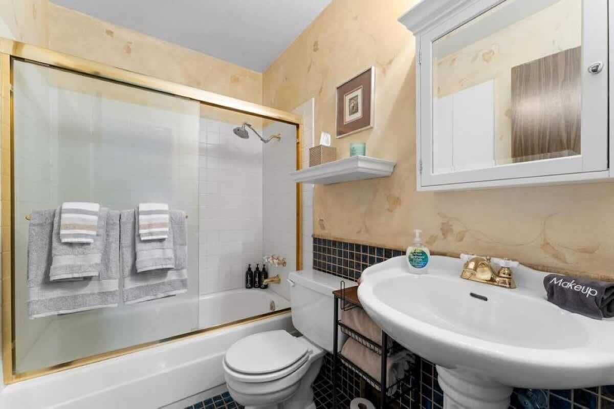 A bathroom with a glass-enclosed shower, a white toilet, a sink with a vanity, and a mirror above the sink.