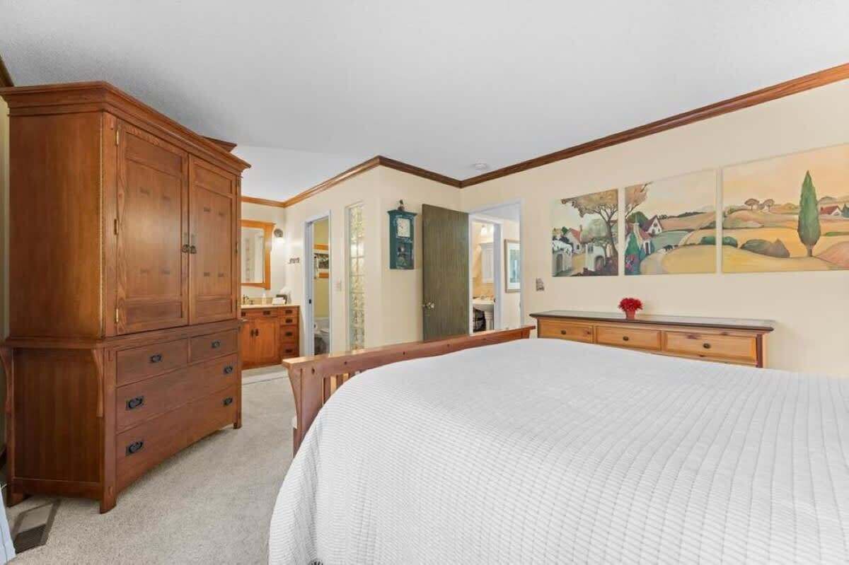 Ein Schlafzimmer mit einem großen Bett, einem Holzschrank und einem Bild an der Wand.
