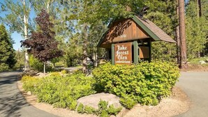 A wooden cabin-style building with a sign reading 'Lake Forest Glen condominiums.' - Two Story Townhome with Hot Tub, Walk to Lake (Tahoe City)