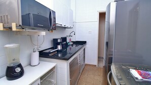 Eine kleine Küche mit Mikrowelle, Kaffeemaschine und Kühlschrank.