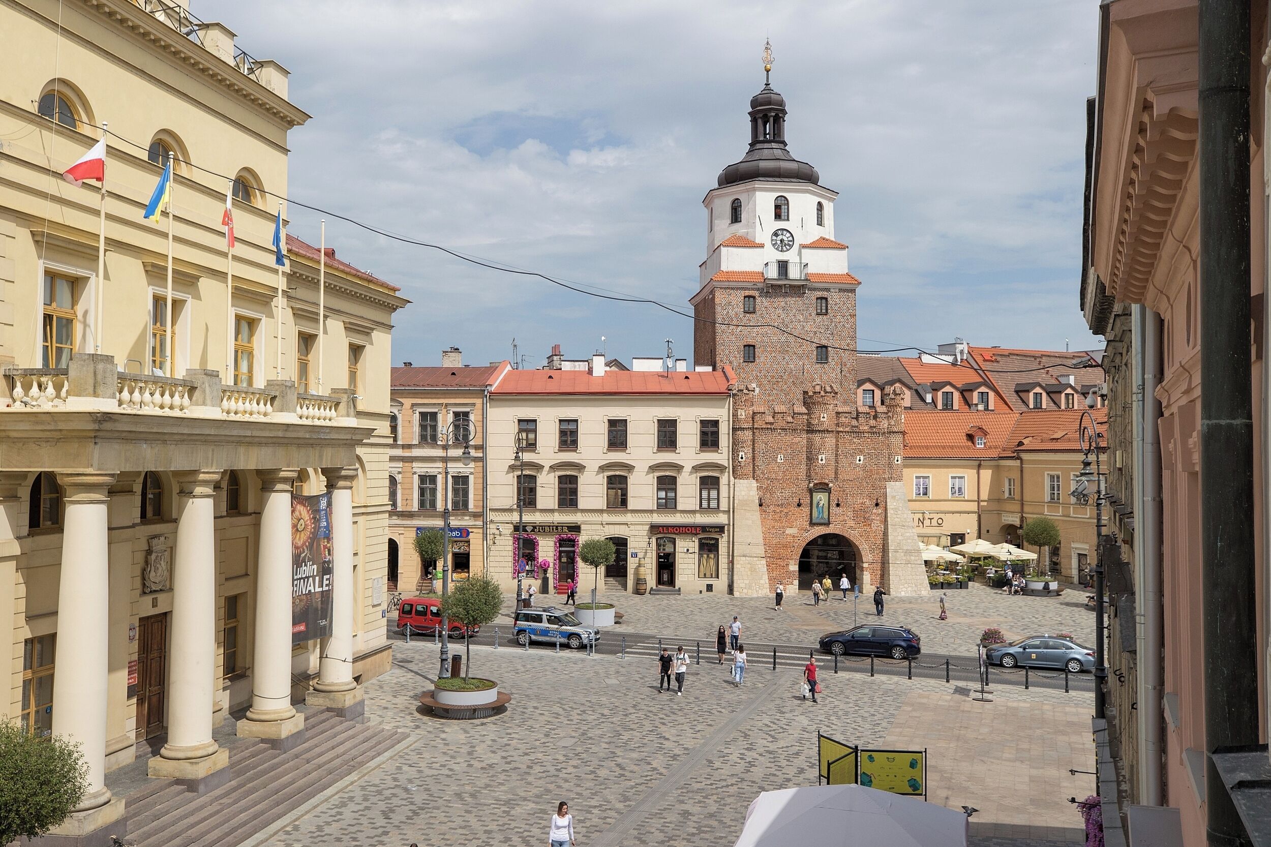 Una plaza histórica con una torre destacada, edificios tradicionales y un espacio abierto en el centro.