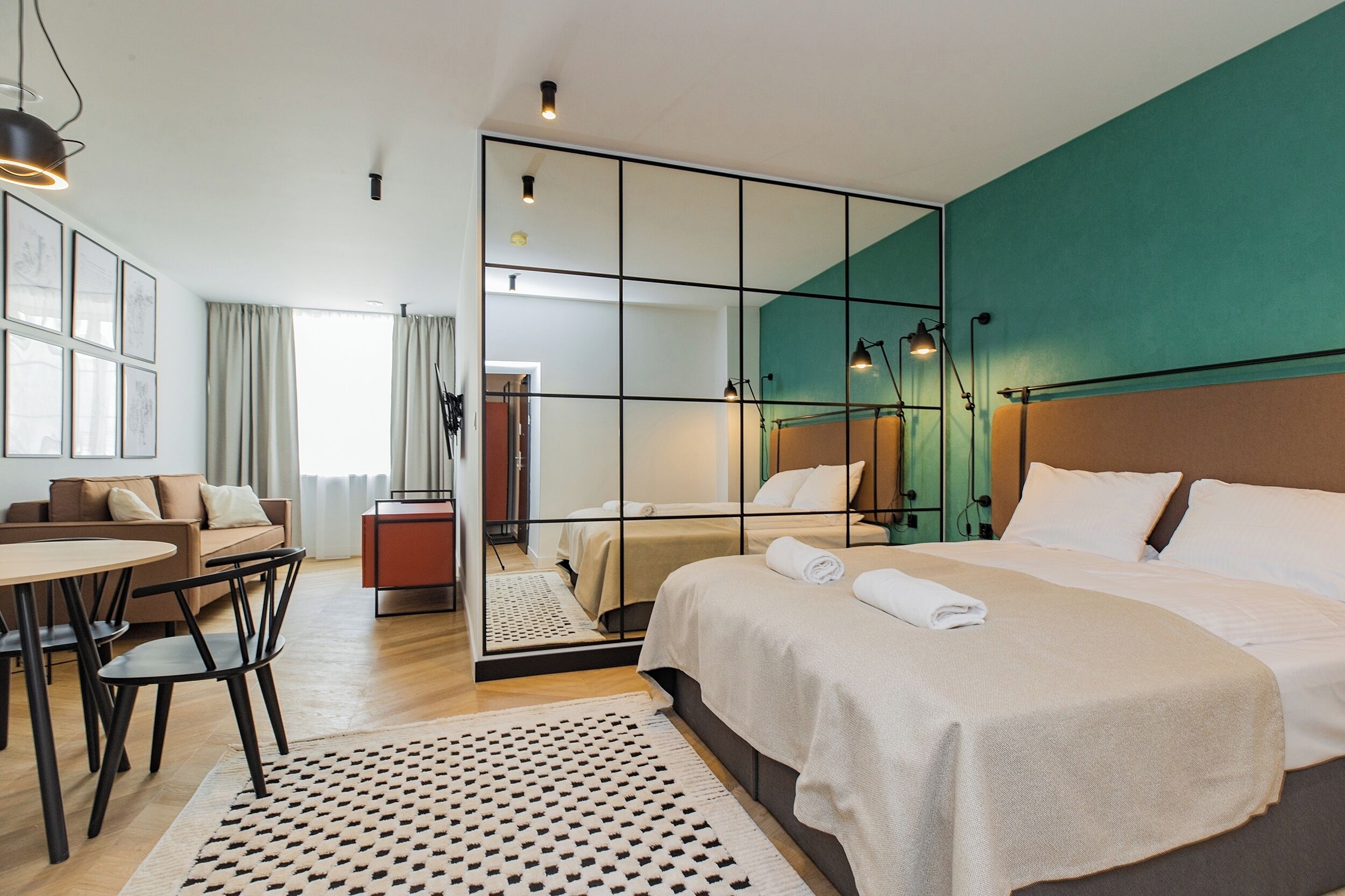 Een moderne hotelkamer met een groot bed, een bank, een eettafel en een spiegel.