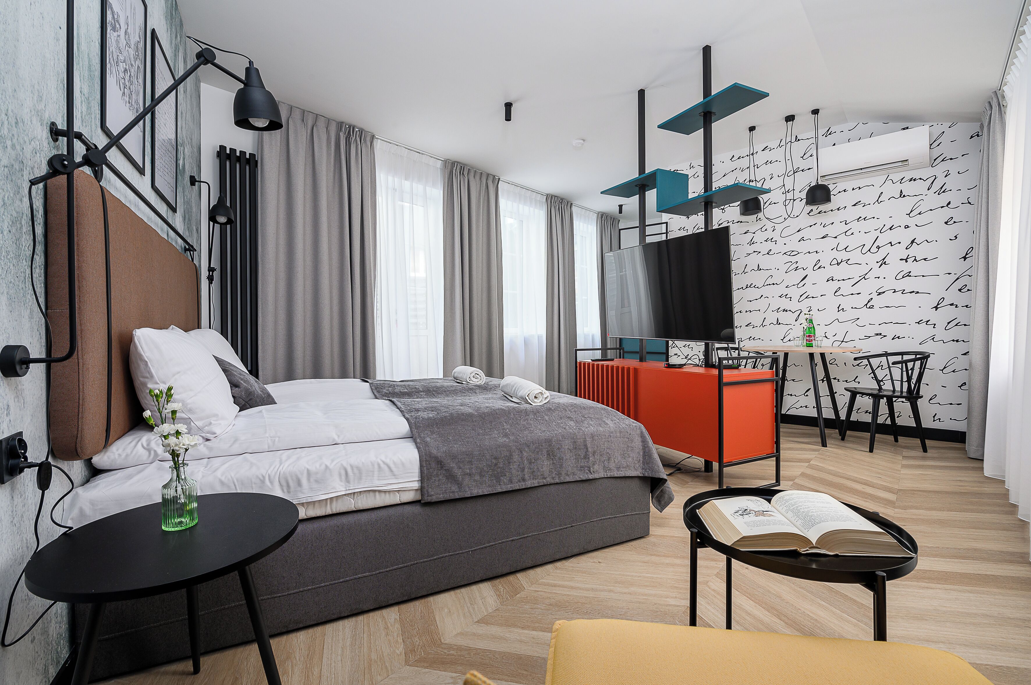 A modern bedroom with a bed, bedside table, and a TV.