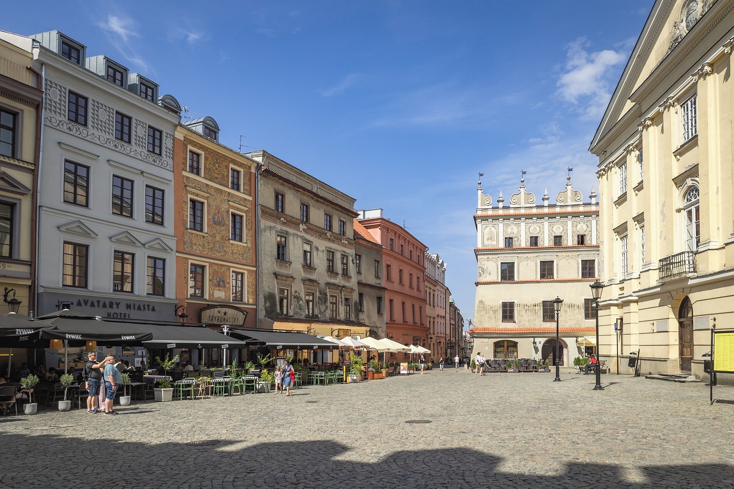 A cobblestone square with historic buildings, outdoor cafes, and a prominent church.