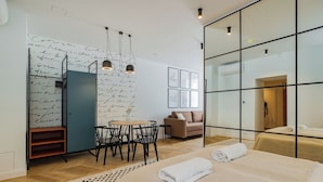 Une chambre d’hôtel moderne dotée d’un grand lit, d’un coin repas avec une table et des chaises, d’un canapé et d’un mur recouvert de notes manuscrites.