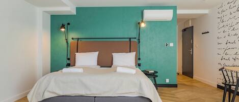 Quarto moderno com cama, abajures, uma mesinha e uma cadeira.