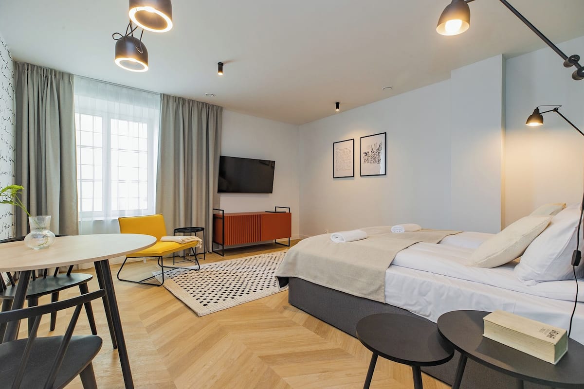 A modern hotel room with a bed, a desk, a chair, and a TV.