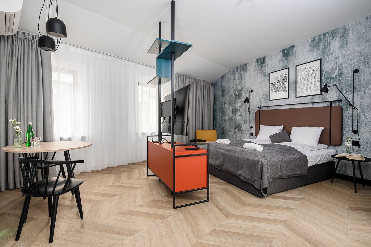 A modern hotel room with a bed, a desk, and a chair.