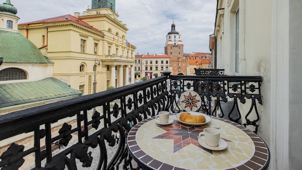 Un balcon avec une table ronde, deux tasses et une assiette contenant une pâtisserie.