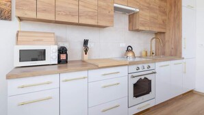 A modern kitchen with wooden cabinets, a microwave, a kettle, and a coffee maker. - Bright Apartment with a Balcony | Lake View, Bicycles (Katowice)