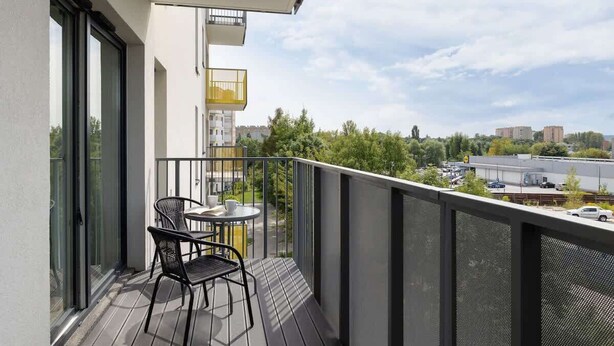 Een balkon met een tafel en stoelen, met uitzicht op een stadsbeeld.