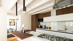 Une cuisine moderne dotée d’un îlot central, d’appareils électroménagers en acier inoxydable et d’un pare-feu en verre.
