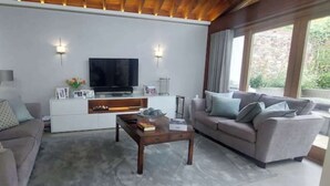 Ein modernes Wohnzimmer mit Flachbildfernseher, zwei Sofas, einem Couchtisch und einer weißen Unterhaltungsecke.