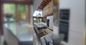 A modern kitchen with a central island, bar stools, and a view of the outdoors. - Sophisticated Seafront 3BD+Suntrap Landscaped Yard (Dublin)