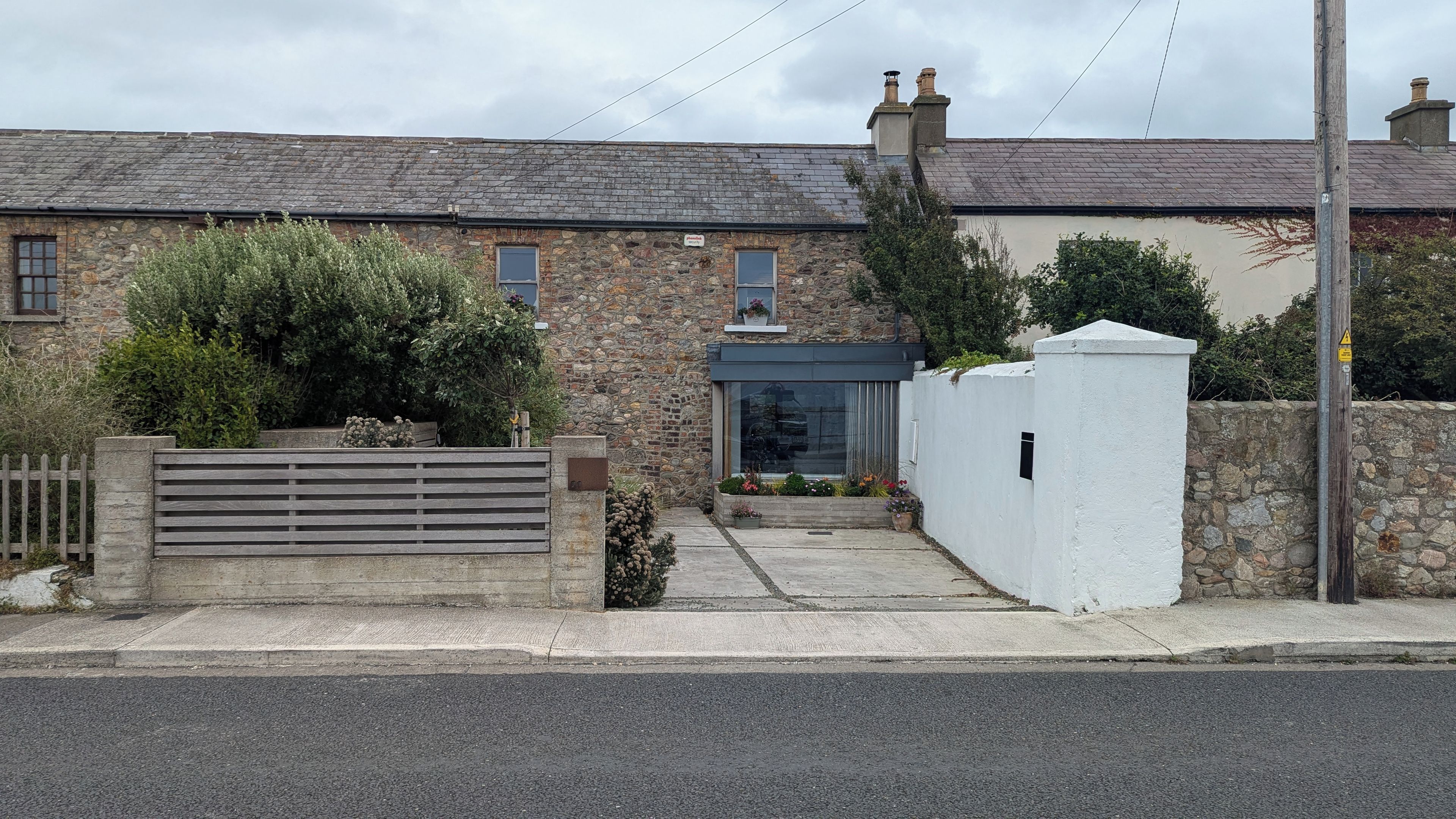 A stone house with a traditional design, a gated entrance, and a small garden area.