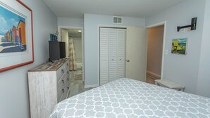 Ein Schlafzimmer mit Bett, Kommode und einer Tür zu einem anderen Raum.