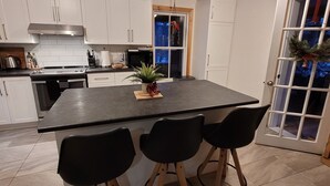 Une cuisine moderne avec des meubles blancs, un plan de travail noir et un îlot central doté de tabourets de bar.