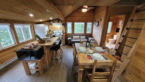 A wooden cabin interior with a kitchen, dining area, and a living room.