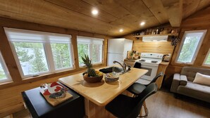 A cozy cabin-style kitchen with wooden walls, a central island, and a dining area.