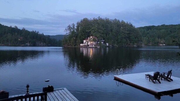 A lakeside property with a dock, a small pier, and a cabin surrounded by dense forest.