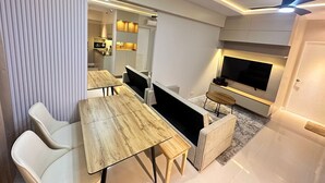 Una sala de estar moderna con comedor, un televisor de pantalla plana en la pared y un ventilador de techo.