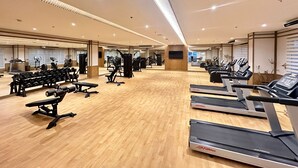 Un gimnasio amplio con varias cintas de correr, máquinas de pesas y pesas libres.