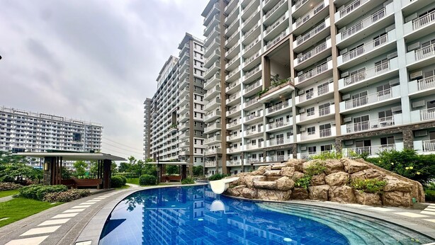 Un edificio residencial con piscina, rodeado de vegetación y paisaje rocoso.