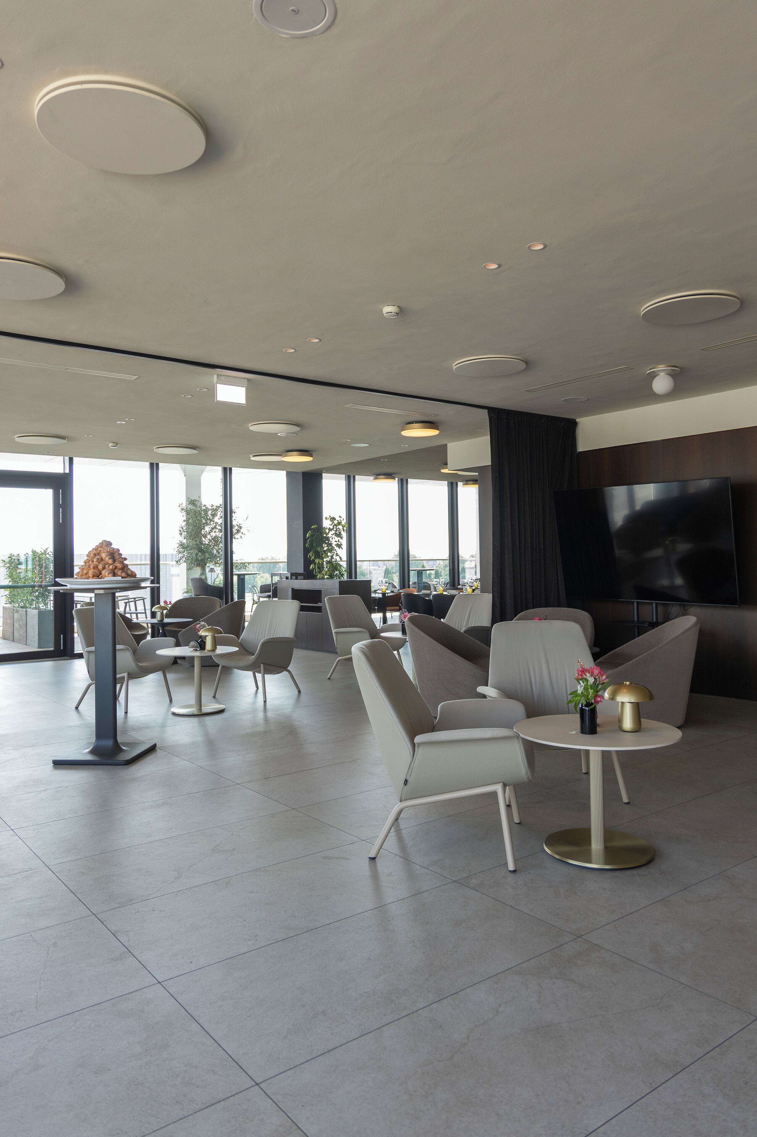 A modern lounge area with seating, a bar, and a large TV screen.