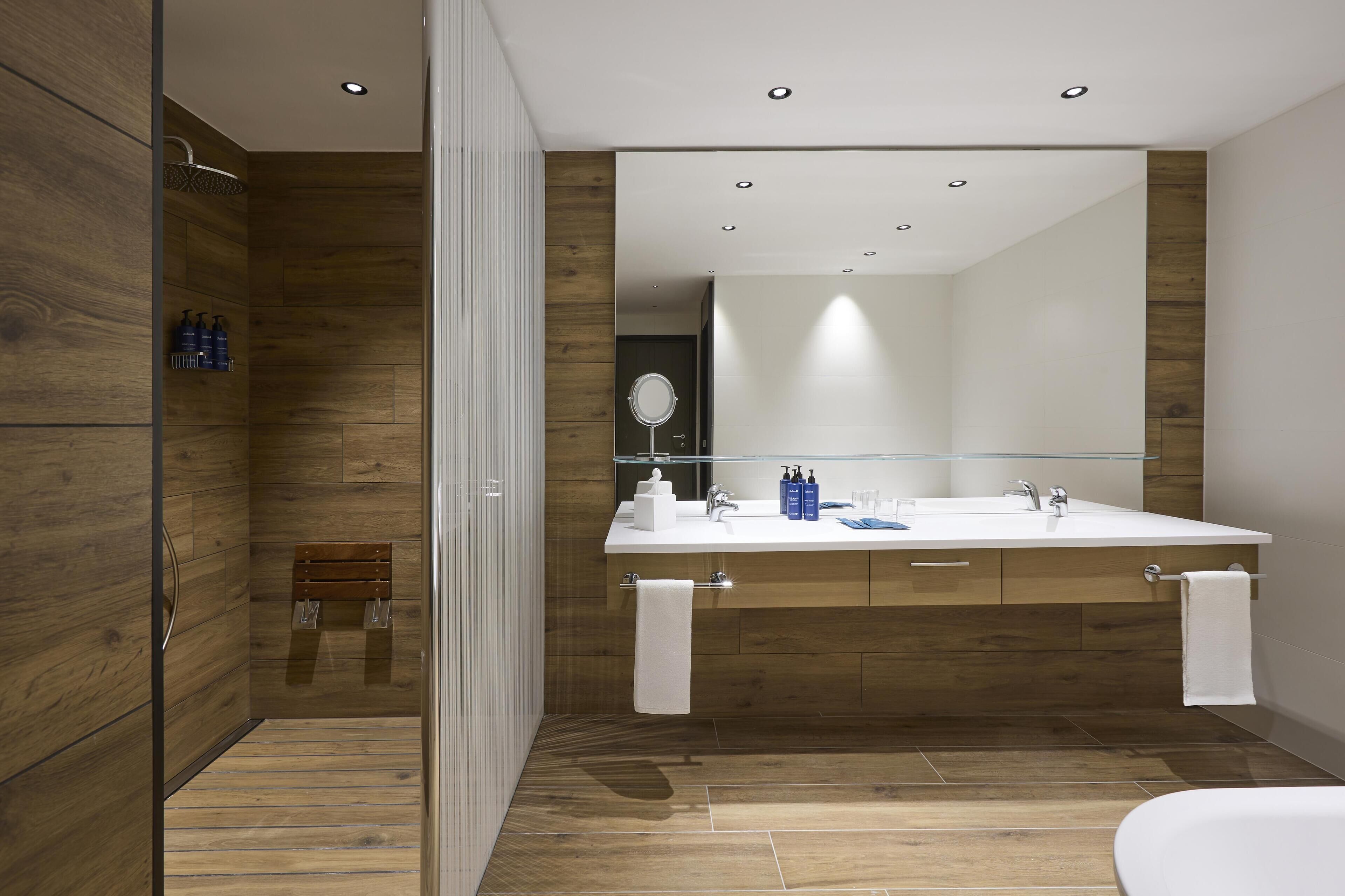 Une salle de bain moderne avec un meuble-lavabo en bois, un grand miroir et un espace douche.