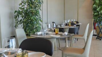 A modern dining area with round tables, chairs, and a large potted plant.