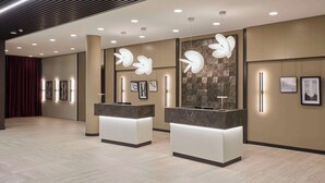 Een moderne receptiebalie met twee balies, in het plafond weggewerkte verlichting en kunstwerken aan de muur.