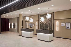 Un'accoglienza moderna con due banchi reception, illuminazione a soffitto incassata e opere d'arte a parete.