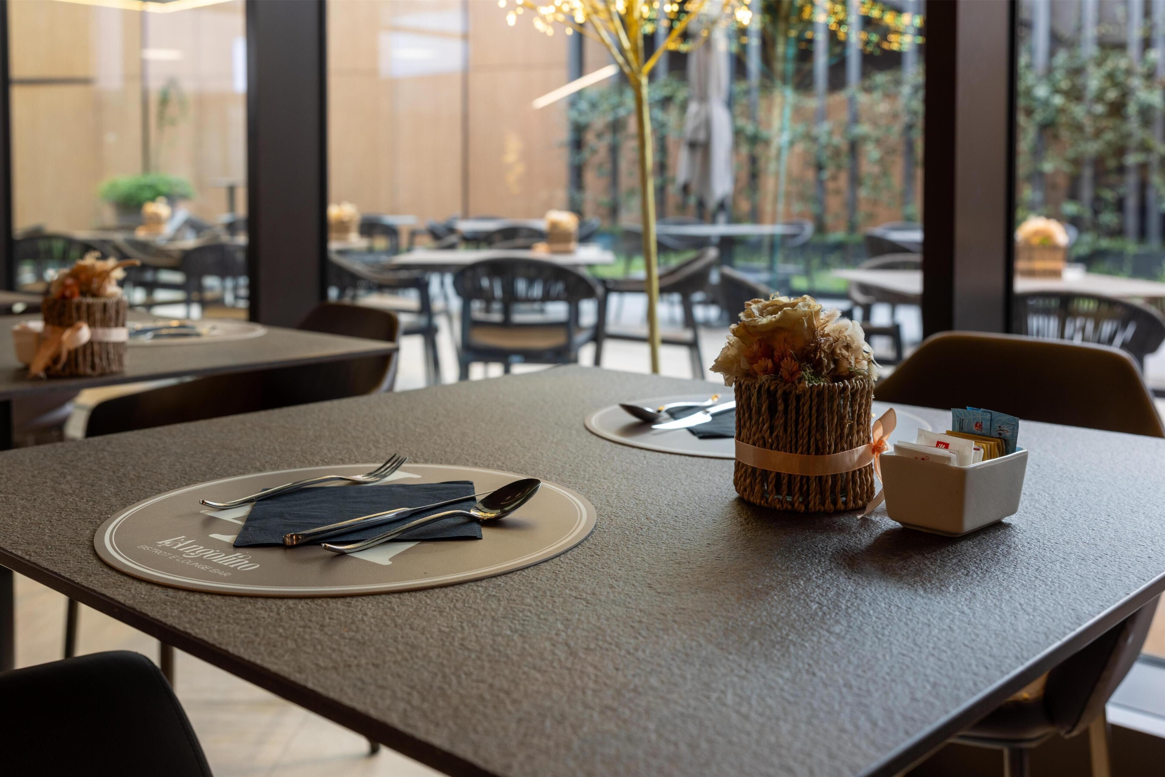 A restaurant setting with tables set for dining, including plates, cutlery, and napkins.