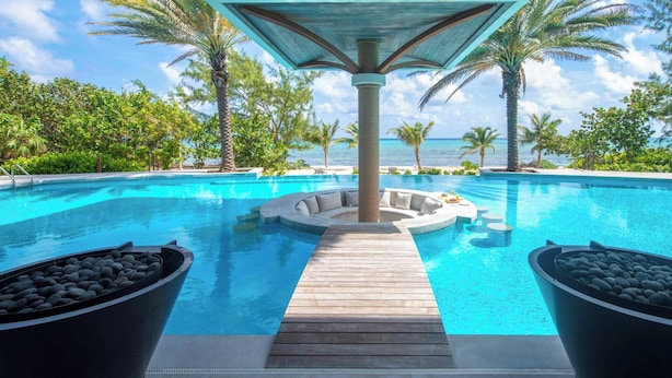 A pool with a wooden deck, lounge chairs, and a view of the ocean.