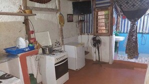 Una cucina compatta con elettrodomestici essenziali, un piccolo lavandino e una ventola.