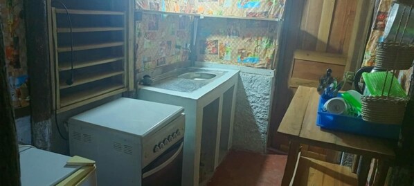 A compact kitchen with a refrigerator, a sink, and a small table with kitchen utensils.