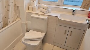 Een kleine badkamer met toilet, wastafel en een raam.