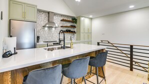 Una cocina moderna con una isla grande, taburetes de bar y una escalera.