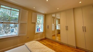 A bedroom with a large wardrobe, a bed, and a window with shutters. - Delightful 3BD Terrace House, Near London Bridge (Greater London)