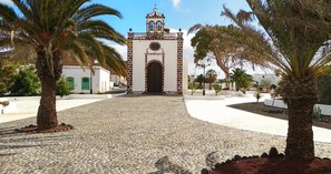 Stunning clock tower stands at the heart of this historic building, surrounded by a charming cobblestone plaza and lush palm trees.