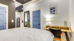 Ein Schlafzimmer mit einem großen Bett, einem Schreibtisch mit Stuhl und einer Tür zu einem Badezimmer.